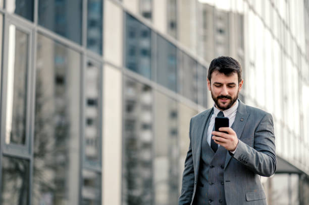 istock Businessman using smart phone and walking down the street 1207984062