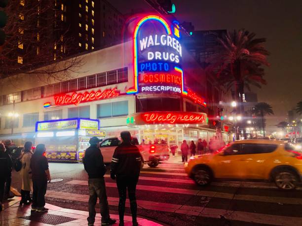 Pedestrians at crosswalk in French Quarter New Orleans, Louisiana, USA, February 2020: pedestrians are seen in the French Quarter at night outside the iconic Walgreens building as the city celebrates Mardi Gras. walgreens stock pictures, royalty-free photos & images