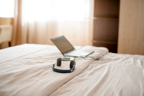 Laptop and headphones on bed