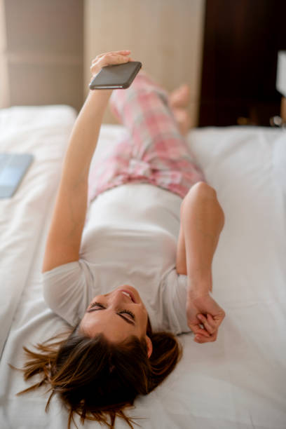 istock Smiling relaxed woman in bed using smartphone 1207989344
