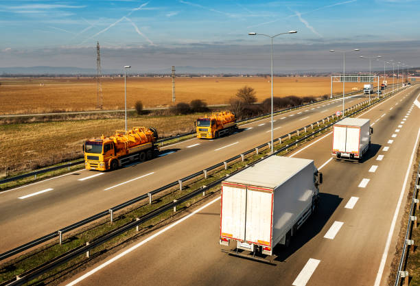 istock Two Orange Tank trucks or Cisterns on a Highway Road passing white Trucks 1207990398