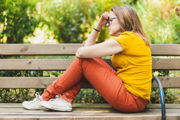 istock Thoughtful woman sitting on bench 1207991540