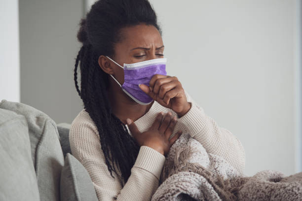 istock Ill woman with face mask coughing lying down and resting. 1207991542