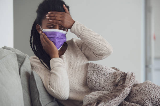 istock Sick woman with face mask checking temperature. 1207992646