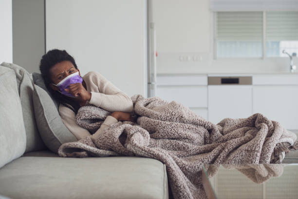 istock Sick woman with face mask coughing, lying down and resting. 1207992699