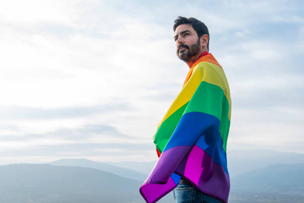 istock handsome man with gay flag on sky background 1207999631