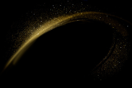 Golden dust glittering wave over black background