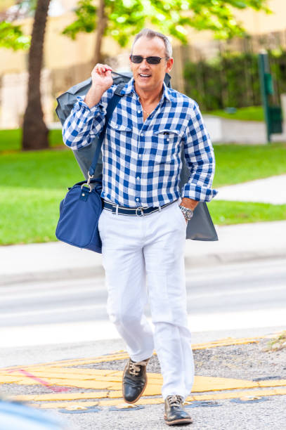 istock Mature executive walking down the street after work carrying a bag with his suit 1208005055