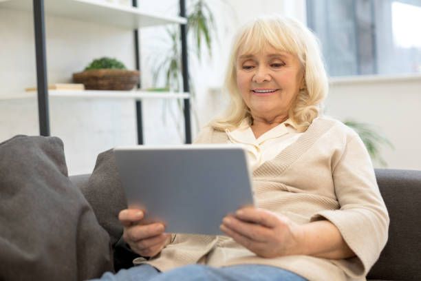 istock Pretty older woman looking at gadget screen at home 1208013492