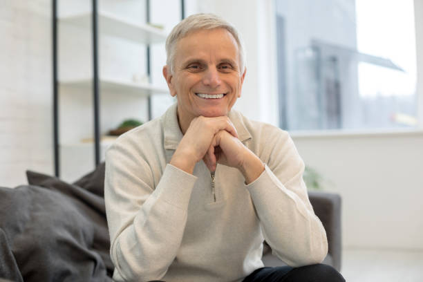 istock Smiling senior man relaxing on sofa at home 1208013704