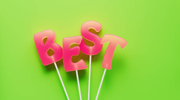 Best written by letter shaped pink lollipops on green background. Horizontal composition with copy space.