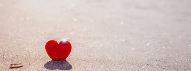 istock Romantic symbol of red heart on the sand beach 1208015976