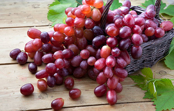 Red grapes in braided basket on wooden table