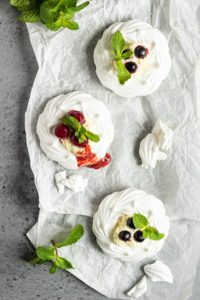 istock Mini Pavlova or meringue nests with whipped cream, berries and mint, selective focus. Grey concrete background. Copy space. 1208017291