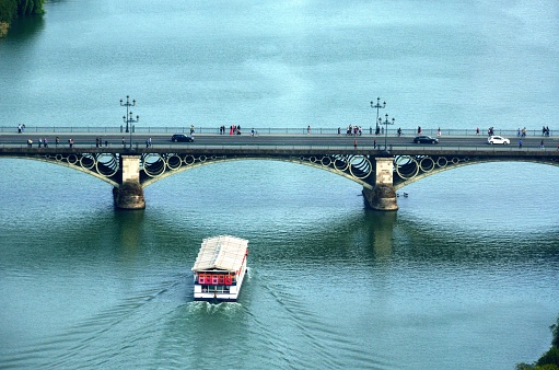 Boat passing under the Triana Bridge in Seville, Andalusia, Spain