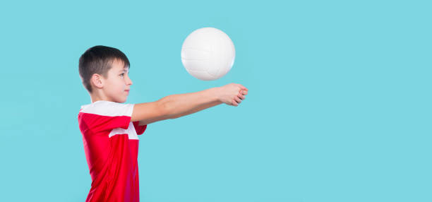 istock Boy playing volleyball isolated in blue. Physical, sport 1208021348
