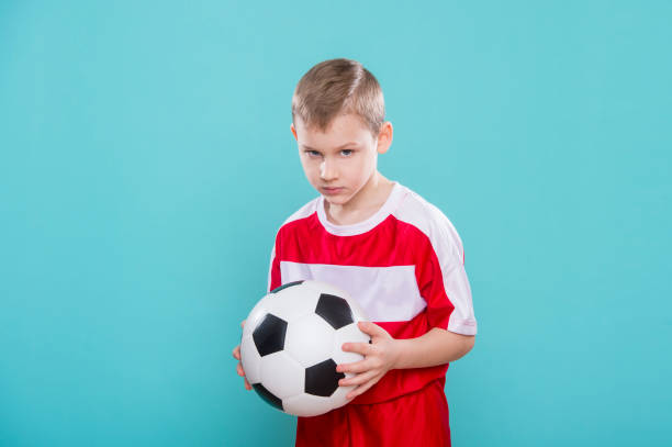 istock Boy With Soccer Ball On blue Background 1208021365