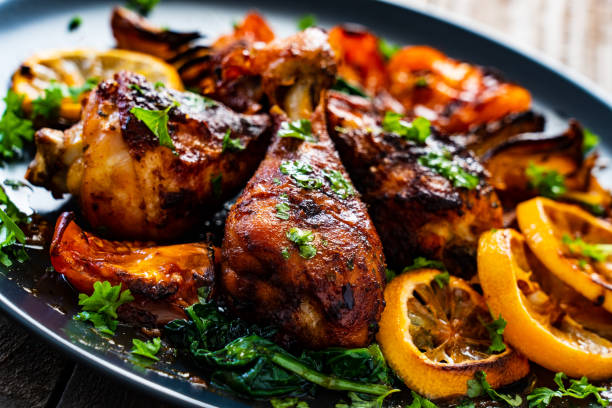 istock Roast chicken drumsticks and vegetables served on black plate on wooden table 1208023633