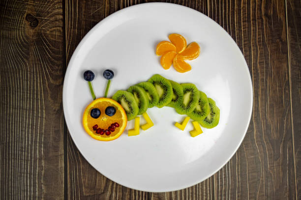 śmieszne robak owocowy na białym talerzu zdrowy deser dla dzieci na drewnianym stole - great white owl zdjęcia i obrazy z banku zdjęć