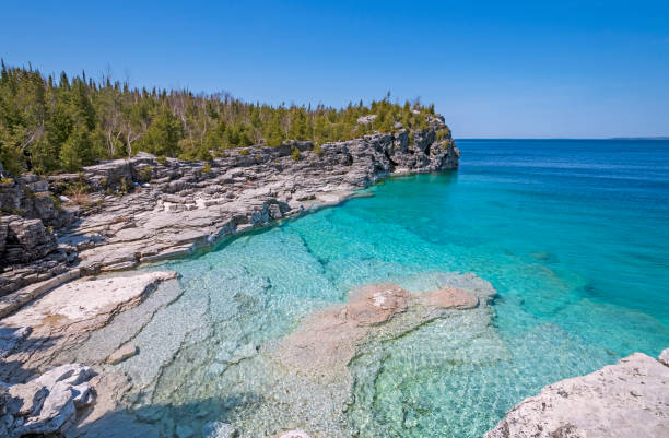 clear waters in a gray cliffed cove - canadian beach imagens e fotografias de stock