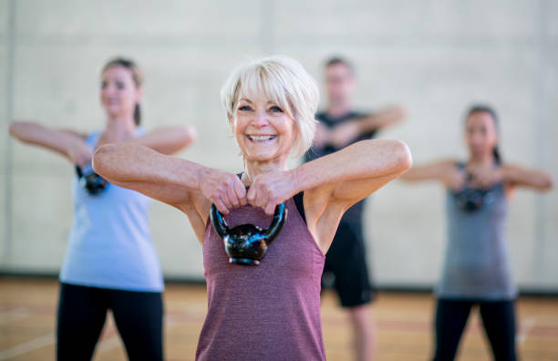 senior woman in fitness class using a kettlebell stock photo - women yoga yoga class mature adult imagens e fotografias de stock