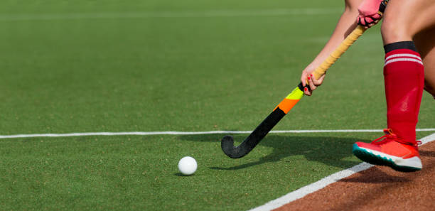 Female field hockey player passing to a team mate on a modern, water artificial astroturf field. Female field hockey player passing to a team mate on a modern, water artificial astroturf field. offense sporting position photos stock pictures, royalty-free photos & images