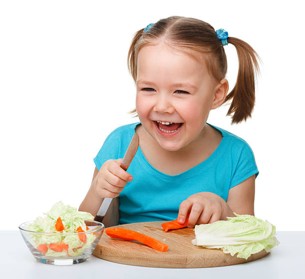 Little girl is cutting carrot for salad stock photo