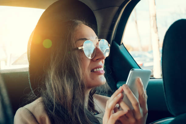 istock Casual woman using smartphone in car 1208039480