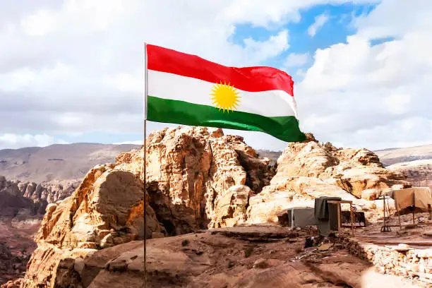 Flag of the unrecognized Republic of Kurdistan in the mountains against the sky and nature of the middle East.
