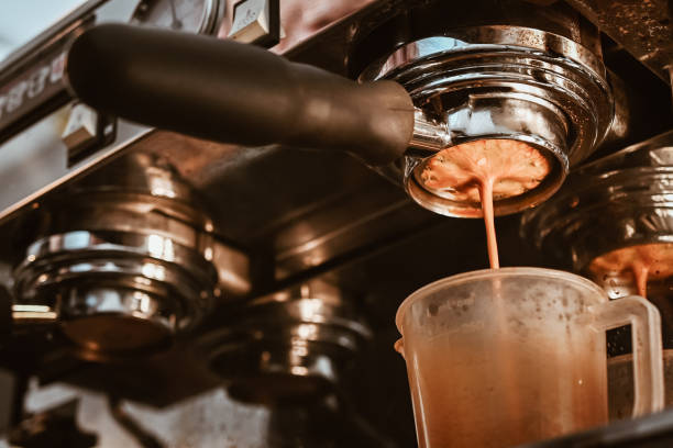 Close up of Espresso machine making an espresso with a "naked" portafilter, directs high-pressure hot water through the coffee puck. The espresso machine is a tool that serves to prepare fresh coffee. glass cup of boiling water stock pictures, royalty-free photos & images