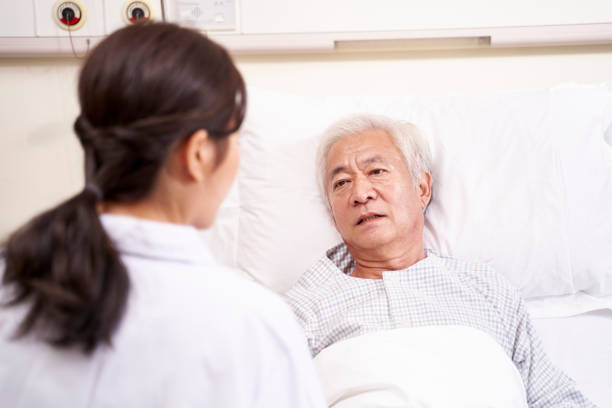 istock asian old man lying on bed talking to doctor 1208062472