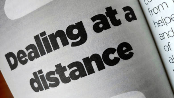 istock Dealing at a distance word printed on a book 1208064835
