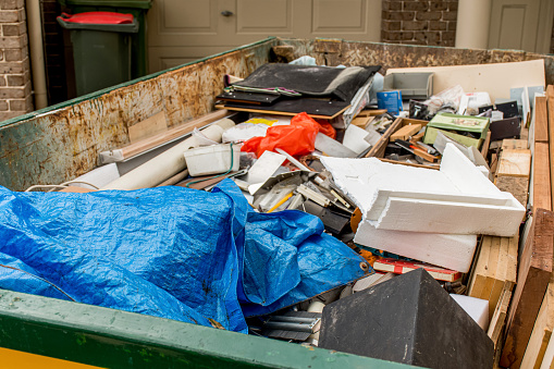 Skip bin full of household waste rubbish on the frond yard