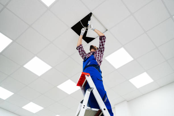 electrician on stepladder installs lighting to the ceiling - ceiling imagens e fotografias de stock