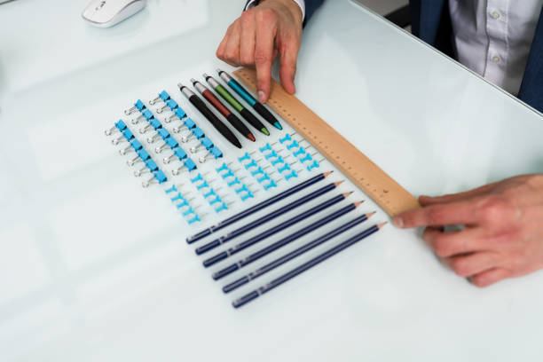 Person Arranging The Clips With Scale A Person's Hand Arranging Pencils And Multi Colored Pushpins In A Row On White Background obsessive stock pictures, royalty-free photos & images
