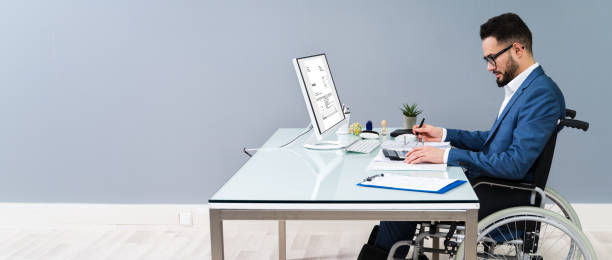 Businessman Sitting On Wheelchair And Using Computer