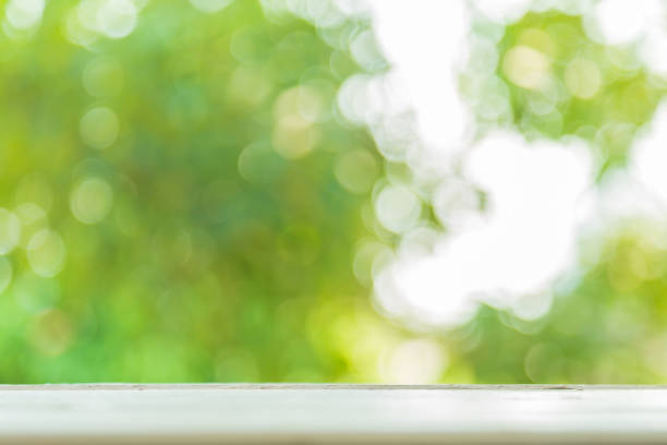 istock Blank white wooden table with green blurred nature background. 1208085869
