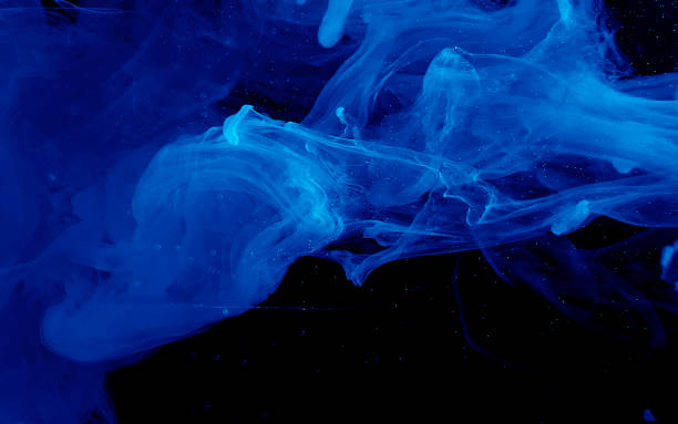 istock Blue watercolor ink in water on a black background. Colored space background. 1208090454