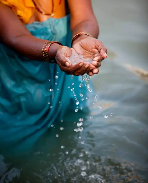 Old woman pouring water of holy river Ganges, Close up view