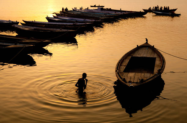 hindu pilgrim offers prayers in the river ganges in varanasi, india - morning river ganges river varanasi imagens e fotografias de stock