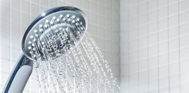 Modern Shower head with running water in white bathroom Modern blue Shower head with running water in white bathroom. Copy space shower head stock pictures, royalty-free photos & images