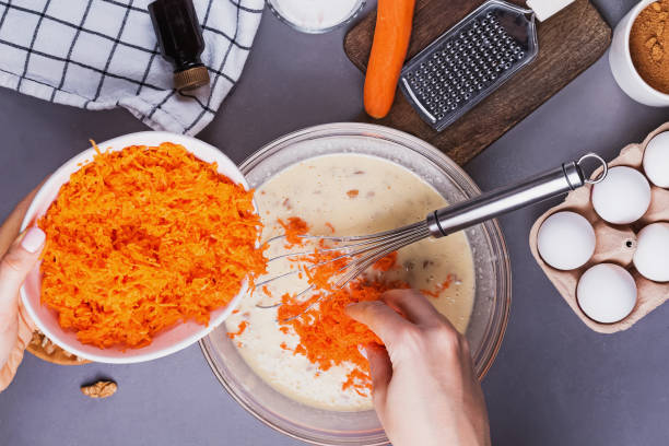 mani della donna che aggiungono carota grattugiata in una ciotola con altri ingredienti - cake carrot carrot cake dessert foto e immagini stock