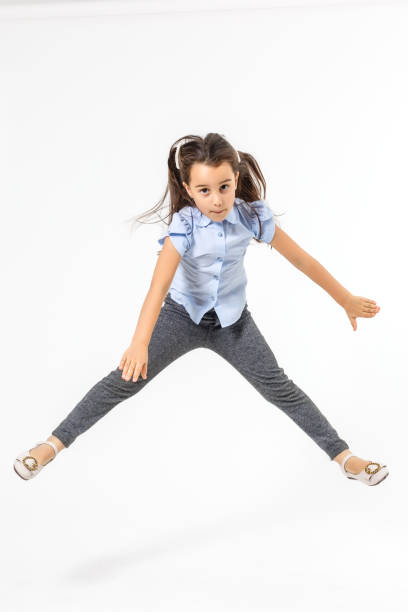 istock Happy schoolgirl jumping high on white background 1208104584