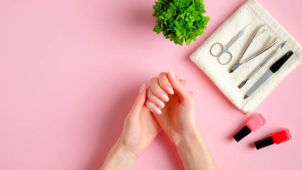 istock Nail studio table with manicure tools, nail polish bottles and woman's hands on pink background. Nail salon workspace concept 1208104848