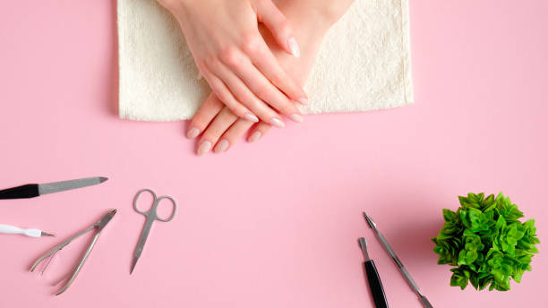istock Nail salon workspace concept. Top view female hands and manicure tools on pink background. Beauty treatment and hand care 1208104877