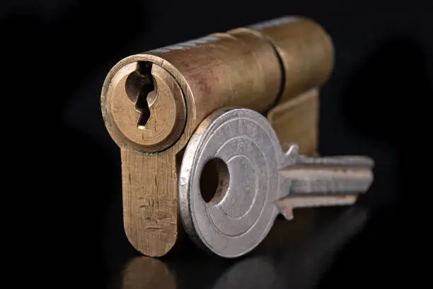 Photo of Brass patent lock and key. Accessories for securing front doors in the household. Dark background.