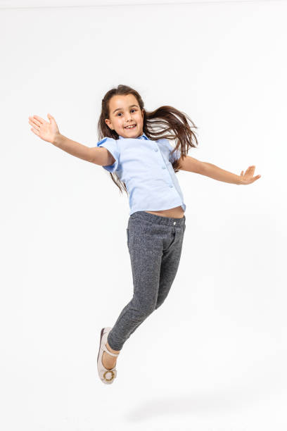 istock little girl jumps on a white background 1208106172