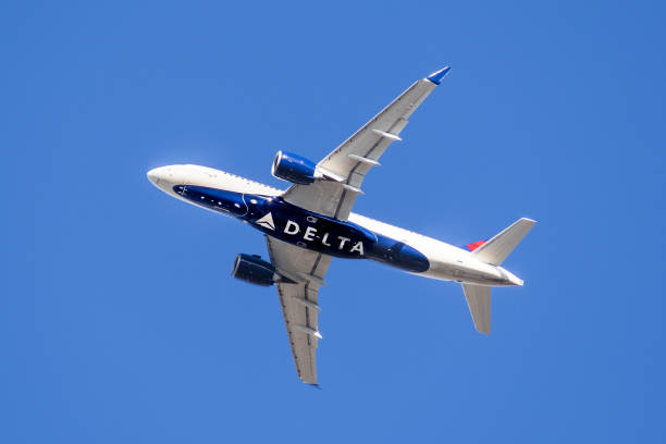 Delta Airlines aircraft in mid flight Feb 18, 2020 San Jose / CA / USA - Delta Airlines aircraft in flight; the Delta Logo visible on the airplanes' underbelly; blue sky background delta stock pictures, royalty-free photos & images