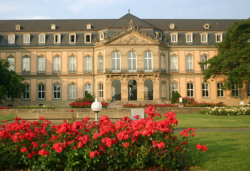 Image taken from the public park next to the New Palace of Stuttgart in Baden-Württemberg, Germany. It was rebuilt after World War 2, and now houses government buildings. There is a person entering the building.