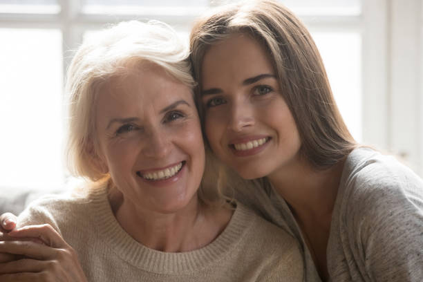istock Middle aged mother grown up daughter embracing looking at camera 1208113567